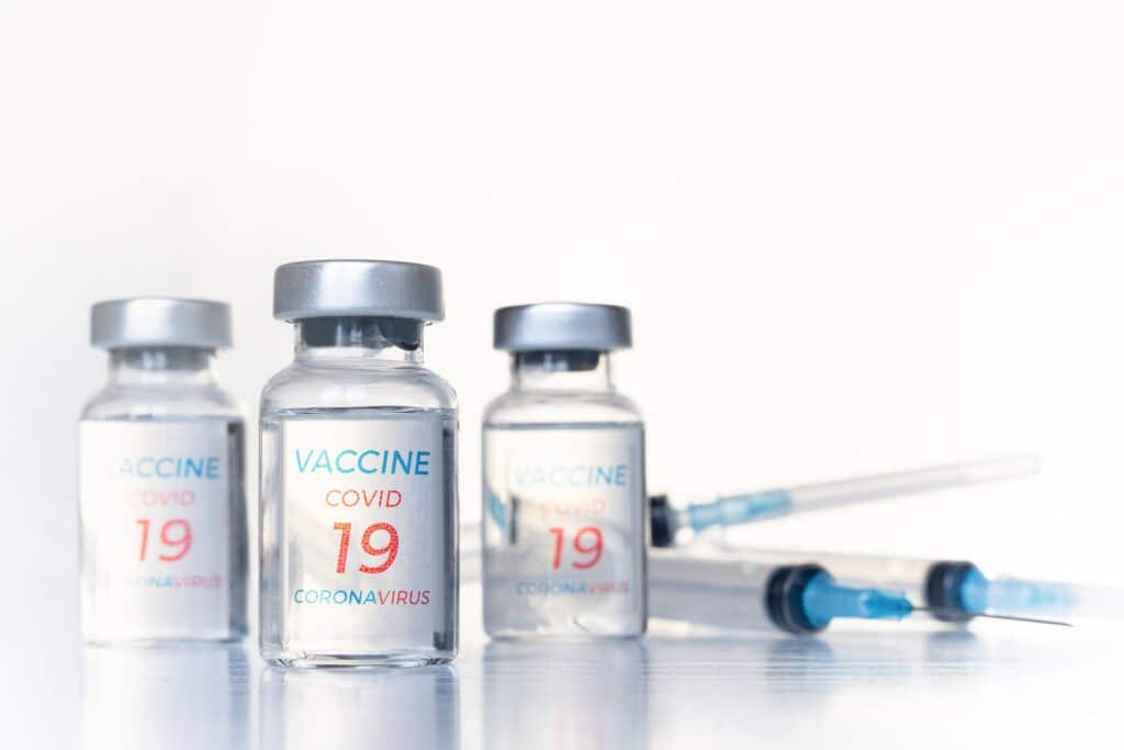 Impfstoffe gegen Covid-19 mit Spritzen im Hintergrund