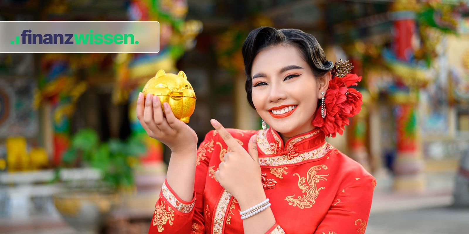 Chinesische Frau in traditioneller roter Kleidung hält ein goldenes Sparschwein hoch.